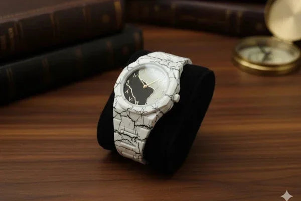 White textured watch on a wooden surface with books and a compass in the background
