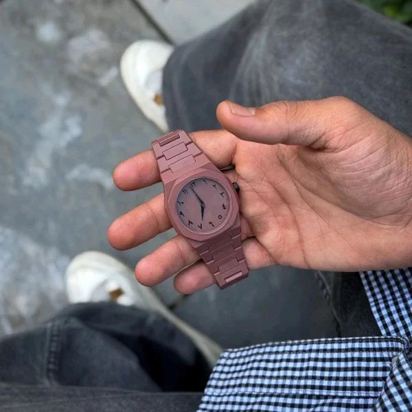 Hand holding a maroon wooden watch with blurred background