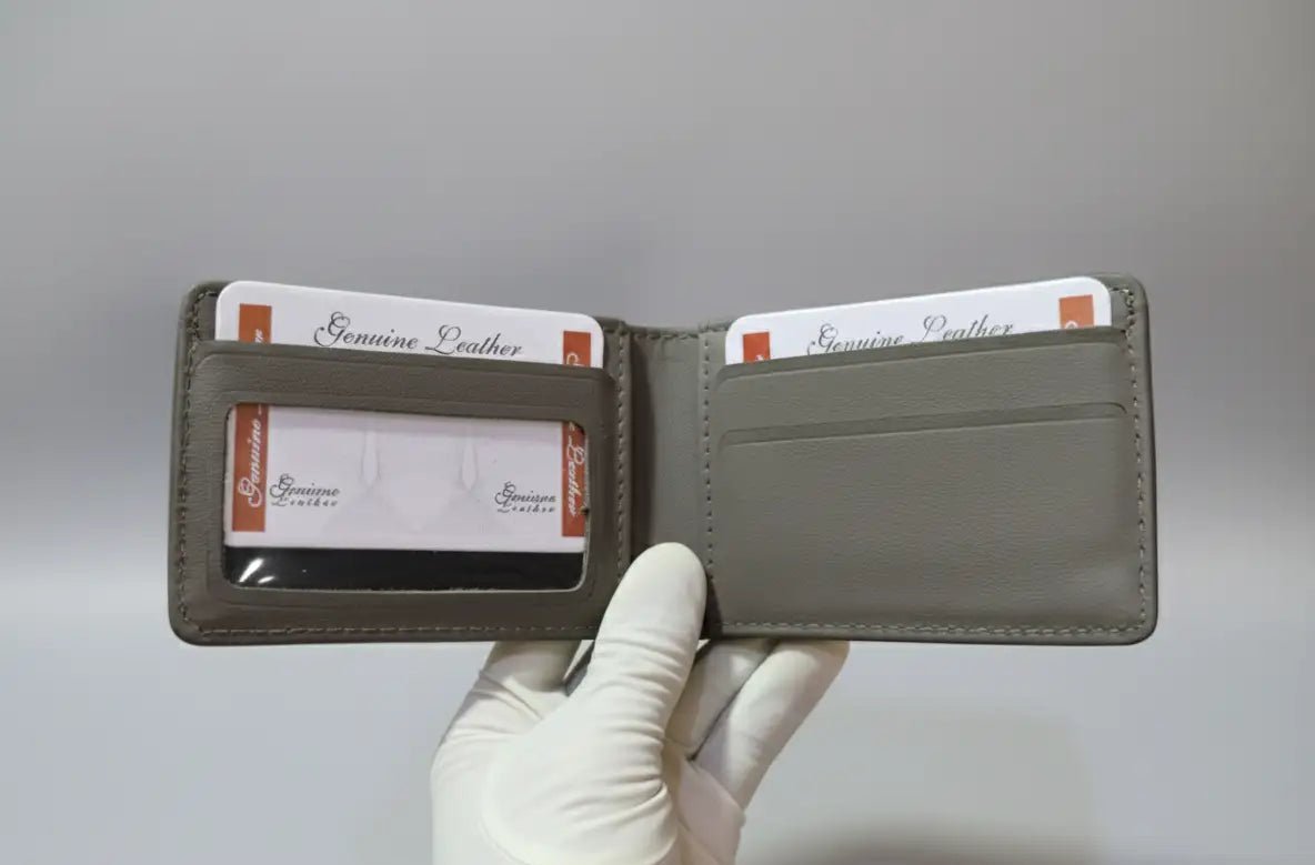 Gray leather wallet held open by a white-gloved hand against a gray background