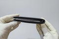 Black plastic component held between gloved hands against a light gray background