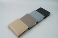 Four different colored wallets arranged in a row on a light gray background
