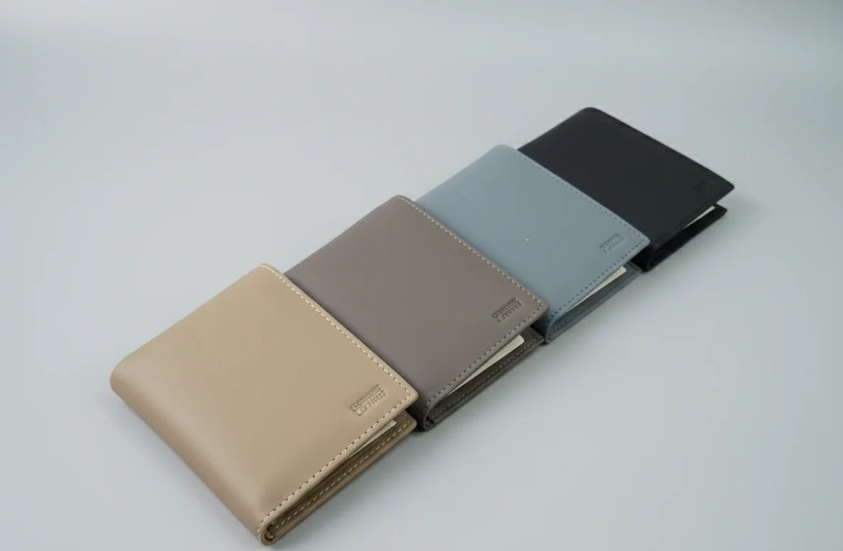 Four different colored wallets arranged in a row on a light gray background