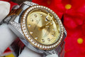 Luxury watch with gold face and silver case against a red floral background