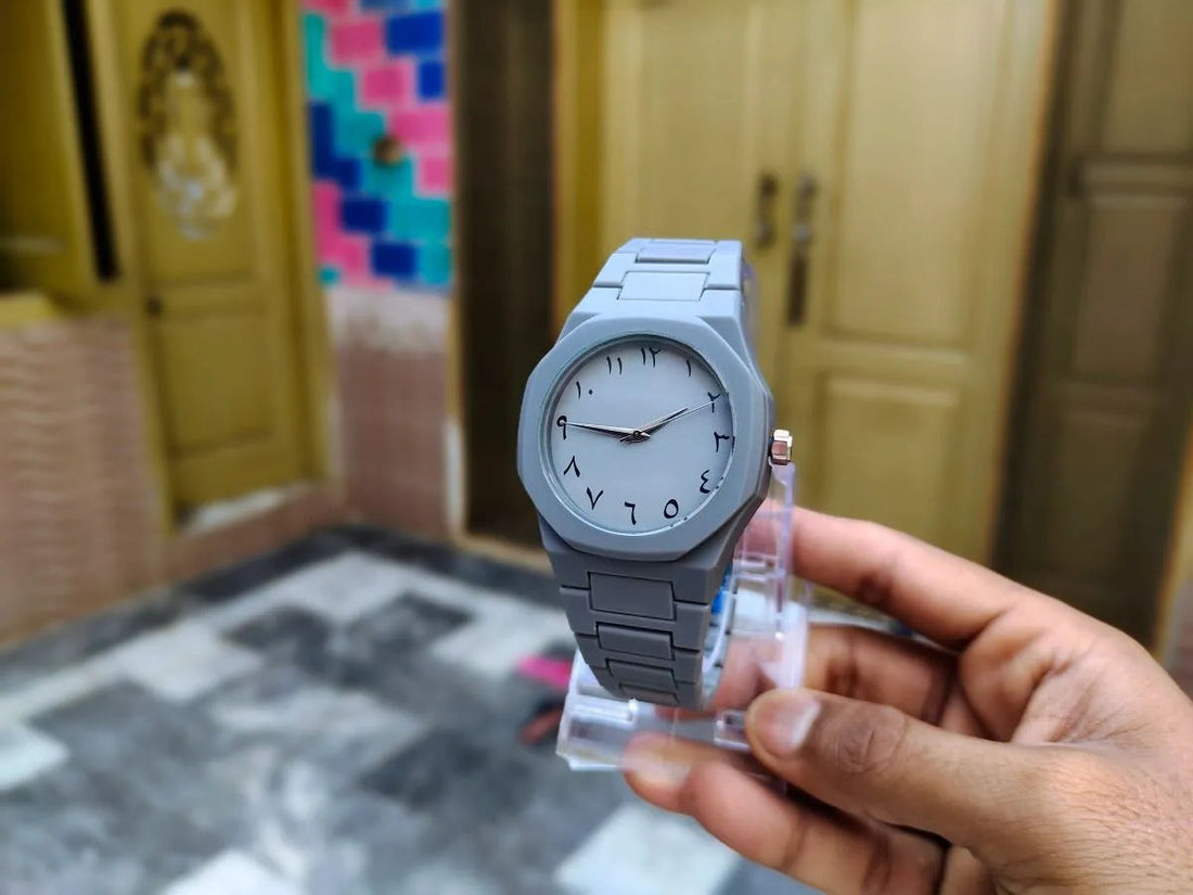 Person holding a watch with a neutral background