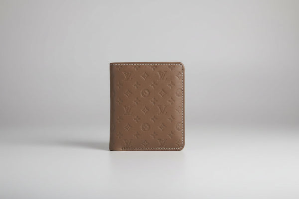 Brown wallet with monogram pattern on a marble surface