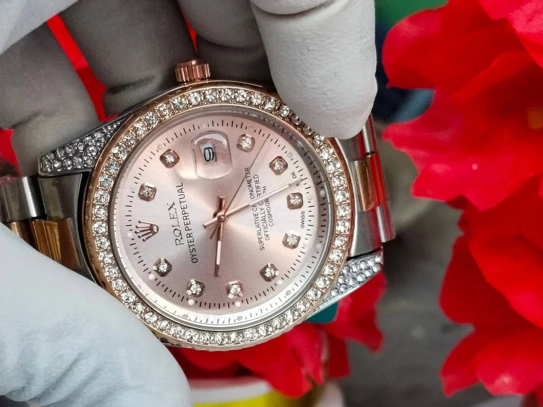 Silver and rose gold watch with gemstones on a white stand with red flowers in the background