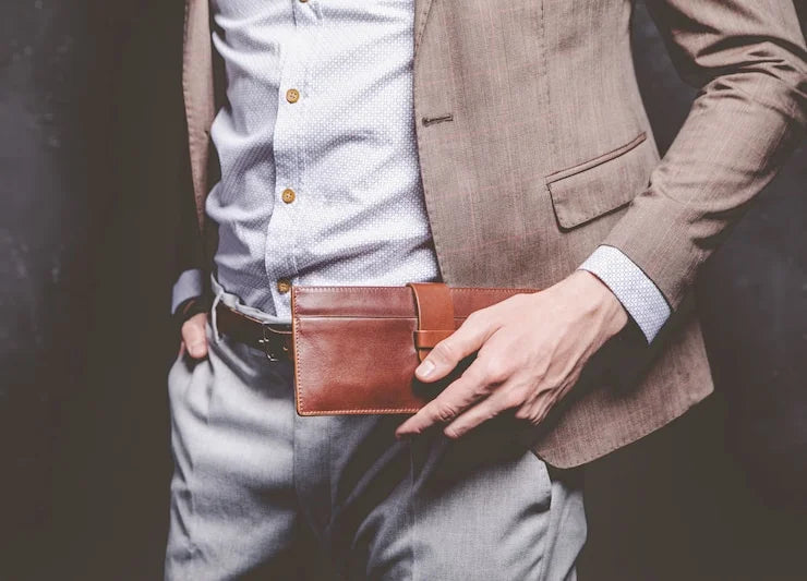 Person wearing a brown blazer and holding a brown wallet.