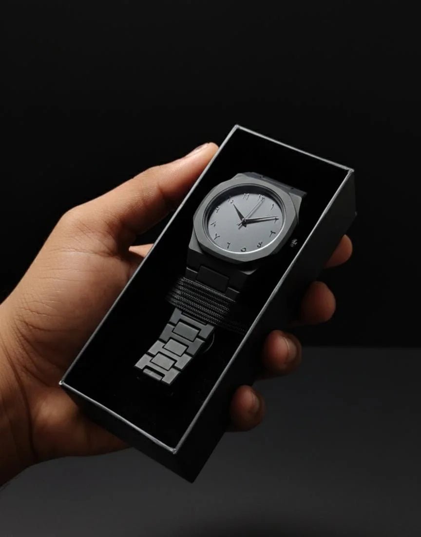 Hand holding a black watch in a box against a dark background