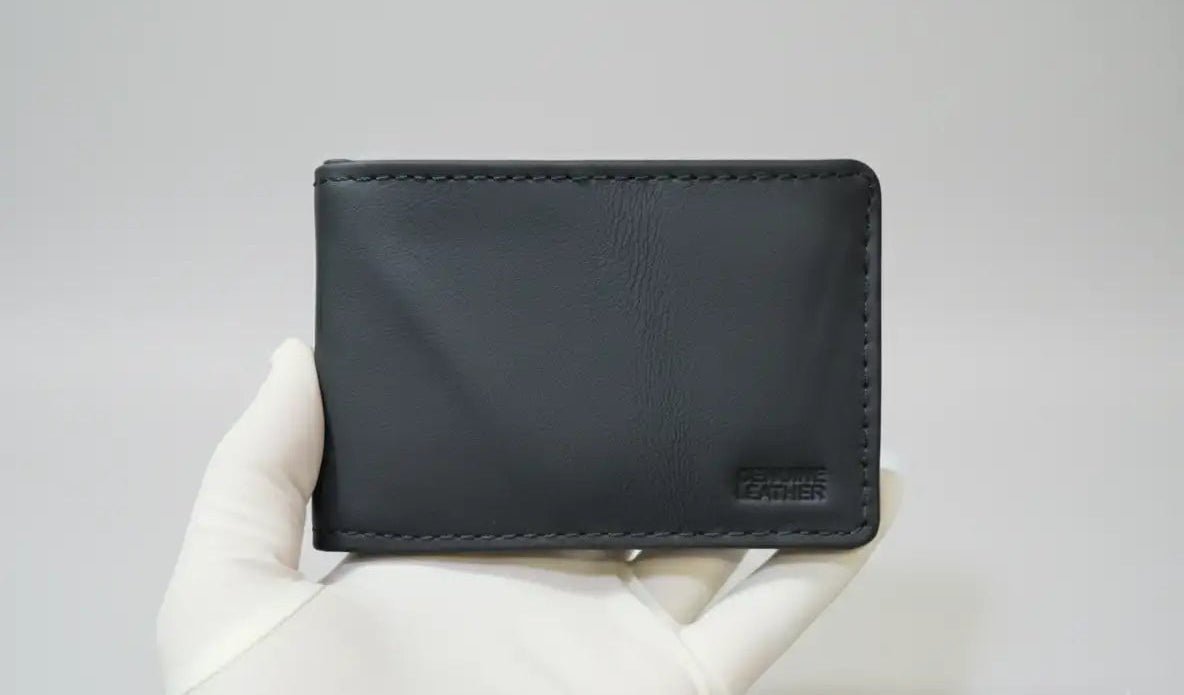 Black wallet held by a gloved hand on a light gray background