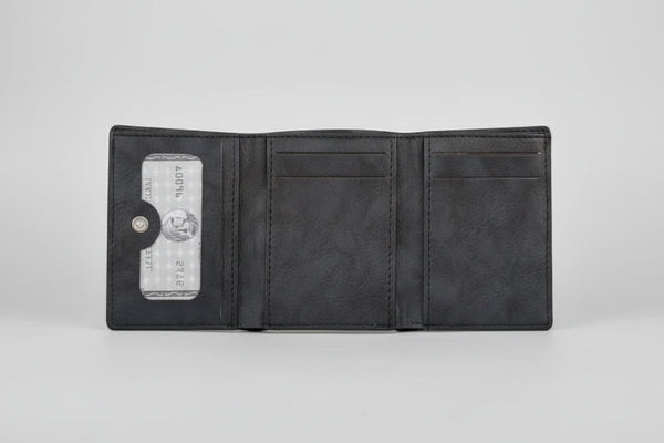 Person holding a black wallet with a blurred natural background