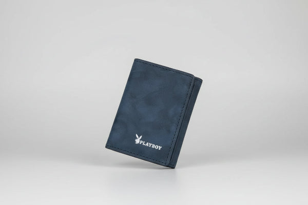 Hand holding a blue wallet with 'Playboy' branding outdoors.