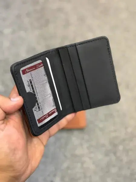 Black wallet held open by a hand with a visible card inside, on a neutral background
