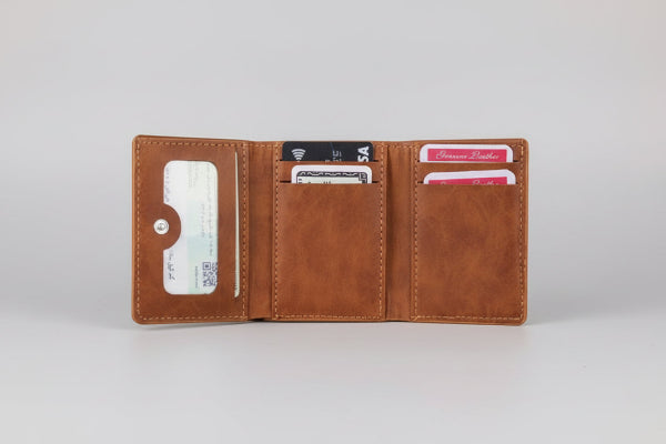 Brown leather wallet with cards held by hands against a blurred natural background