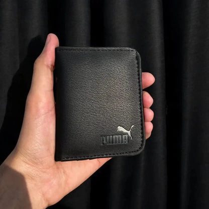 Black Puma wallet held in a hand against a black background