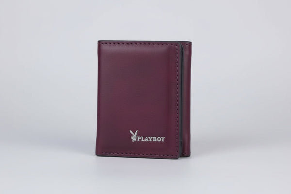 Hand holding a purple Playboy wallet with a blurred natural background